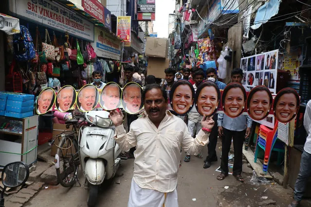 A man wears cut-outs of U.S.President-elect Joe Biden and Vice President-elect Kamala Harris and walks on a street in Chennai, India, Wednesday, January 20, 2021. The inauguration of Biden and Harris is scheduled be held Wednesday. (Photo by R. Parthibhan/AP Photo)