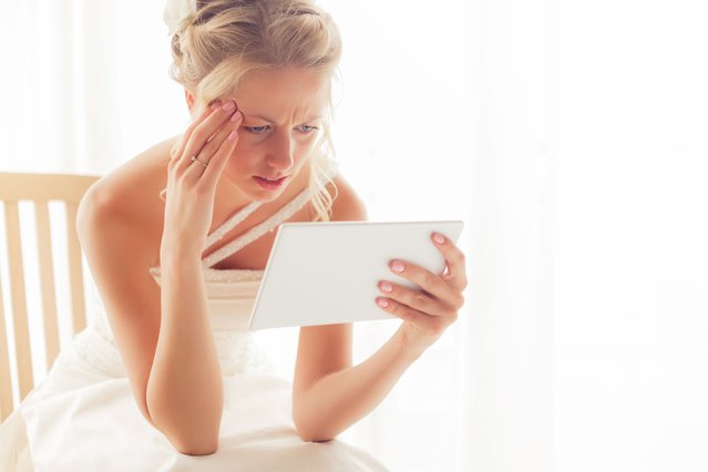 Worried bride looking at tablet. (Photo by grinvalds/Getty Images)