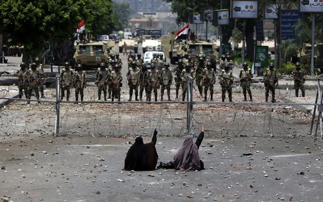 Egyptian supporters of deposed president Mohamed Morsi sit in front of barbed wire fencing that blocks the access to the headquarters of the Republican Guard in Cairo on July 8, 2013. Forty-two loyalists of Egypt's ousted president were killed while demonstrating against last week's military coup, triggering an Islamist uprising call and dashing the army's hopes for an interim civilian administration. (Photo by Mahmud Hams/AFP Photo)