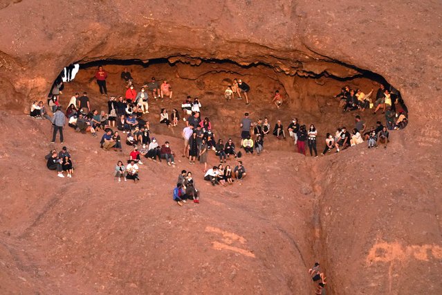 Hikers watch the sunset from Hole-in-the-Rock at Papango park Saturday, February 27, 2021, in Phoenix. (Photo by Charlie Riedel/AP Photo)
