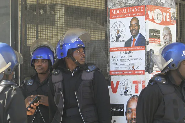 A Zimbabwean Riot policeman looks at the campaign poster of main opposition leader, Nelson Chamisa outside the party headquarters in Harare, Zimbabwe, Thursday, August 2, 2018. Zimbabwe's acting President said Thursday that his government had been in touch with the main opposition leader in an attempt to ease tensions after election related violence in the capital. (Photo by Tsvangirayi Mukwazhi/AP Photo)