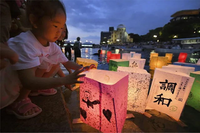 A girl releases paper lanterns on the Motoyasu river facing the gutted Atomic Bomb Dome in remembrance of atomic bomb victims on the 73rd anniversary of the bombing of Hiroshima, western Japan, August 6, 2018, in this photo taken by Kyodo. (Photo by Kyodo News via Reuters)