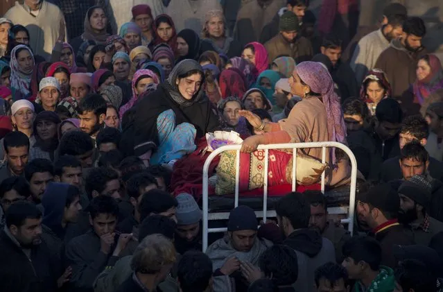 The mother  and sister of  Farooq Ahmed Bhat wail during his funeral procession in Palhalan, some 35 kilometers (22 miles) north of Srinagar, Indian controlled Kashmir, Tuesday, February 10, 2015. Hundreds of angry protesters clashed with Indian authorities on Tuesday at the funeral of the young man killed during a demonstration in disputed Kashmir. Separatists called for a daylong strike in the tense Himalayan territory. (Photo by Dar Yasin/AP Photo)