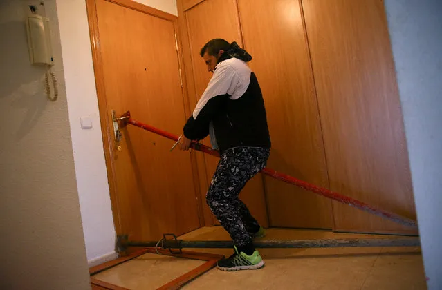 Jose Antonio Rojas Marcos, 32, blocks his entrance door before Spanish riot policemen evicted the family from their home in Parla, outside Madrid, Spain, November 29, 2016. Rojas Marcos, his wife Jessica Guabala de la Cruz, 28, and their two children, 10 and 3, had been living in the flat, that belongs to Lazora, for about 2 years and 7 months and stopped paying their rent, when they both lost their jobs. (Photo by Andrea Comas/Reuters)