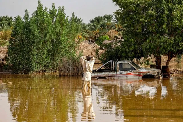 A man reacts as he stands in a flooded area near a partially-immersed truck in al-Sagai north of Omdurman on August 6, 2023. (Photo by AFP Photo/Stringer)