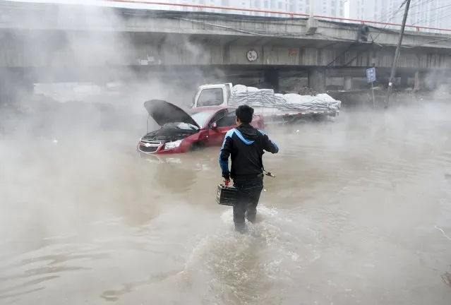 A rescue worker wades towards a trapped car under an expressway after water overflowed from a jammed used water storage well, in Xi'an, Shaanxi province, China, January 6, 2016. (Photo by Reuters/Stringer)