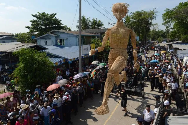 Residents watch an eight-metre tall wicker puppet from the French cultural group L'Homme Debout parade in Yangon city's Dala township on December 2, 2016 to mark the opening of the Mingalabar Festival. (Photo by Romeo Gacad/AFP Photo)