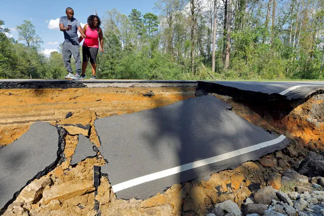 Passersby look at a section of washed-out road damaged by flood waters in the aftermath of Hurricane Florence, now downgraded to a tropical depression, in Currie, North Carolina, U.S., September 18, 2018. (Photo by Jonathan Drake/Reuters)