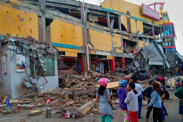 Residents stand in front of a damaged shopping mall after an earthquake hit Palu, Sulawesi Island, Indonesia on September 29, 2018. (Photo by Rolex Malaha/Antara Foto via Reuters)