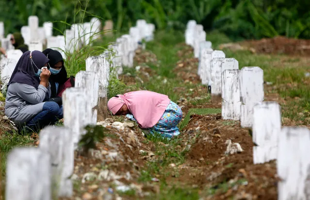 A woman cries before her husband's grave at a cemetery for victims of COVID-19 in Jakarta, Indonesia, 17 May 2021. The Jakarta government allowed residents toresume visits to the city's Public Cemetery on 17 May amid the ongoing coronavirus pandemic. (Photo by Adi Weda/EPA/EFE)