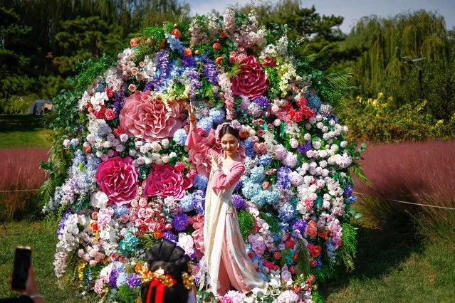 A woman wearing traditional Hanfu Chinese clothing poses for photographs along flowers during a Hanfu festival to mark the Mid-Autumn Festival in Beijing, China on September 29, 2023. The Mid-Autumn Festival or Moon Festival, is a traditional holiday celebrated on 15th day of the 8th lunar month. (Photo by Mark R. Cristino/EPA)