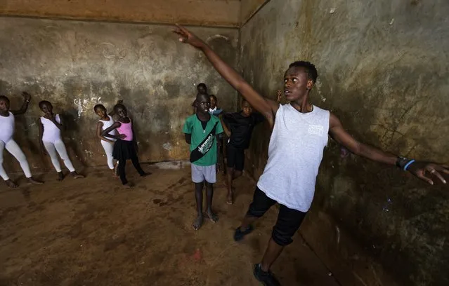 In this photo taken Friday, December 9, 2016, young ballerinas receive instruction from Kenyan ballet dancer Joel Kioko, 16, right, in a room at a school in the Kibera slum of Nairobi, Kenya. (Photo by Ben Curtis/AP Photo)