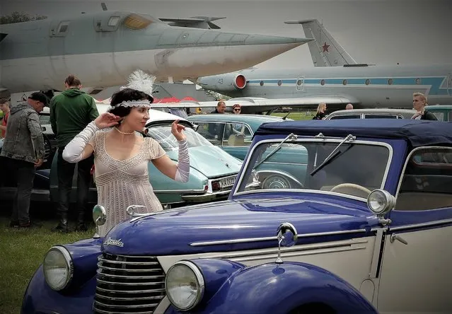 A woman dressed in historical costume poses near of an old car during the “OldCarLand” motor show in Kiev, Ukraine, 28 May 2021. Hundreds of old and exclusive cars and motorbikes of different world producers are presented at the exhibition, which takes place in a venue of the Ukrainian Aviation museum. (Photo by Sergey Dolzhenko/EPA/EFE)