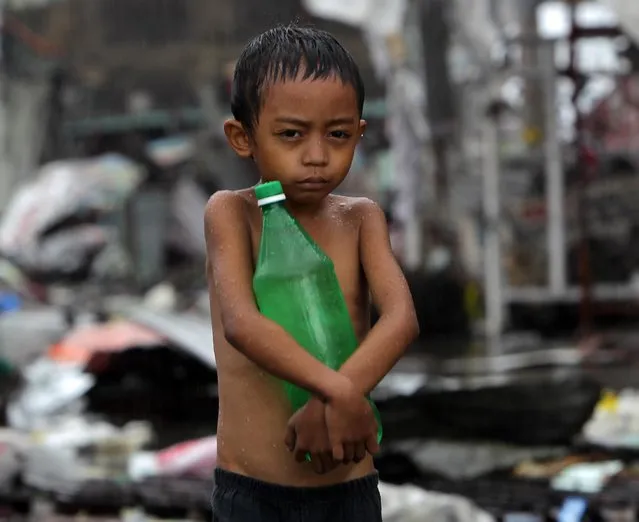 A Filipino kid holding a bottle of water walks under the rain in the super typhoon devastated city of Tacloban, Leyte province, Philippines, 12 November 2013. International aid poured in for the Philippines as authorities stepped up efforts to reach survivors driven to looting after one of the world's strongest typhoons devastated their towns. A tropical depression brought heavy rains over the central and eastern Philippines, where provinces badly hit by Haiyan are located, raising concerns that relief operations would be hampered. (Photo by Francis R. Malasig/EPA)