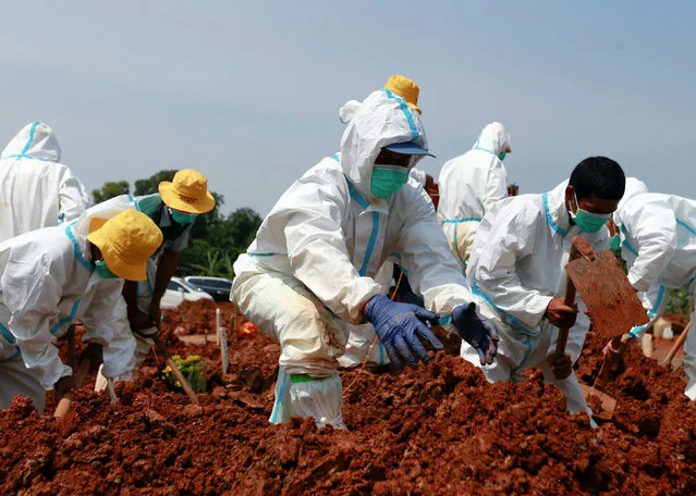 Gravediggers wearing personal protective equipment (PPE) bury a coffin at a Muslim burial area provided by the government for coronavirus disease (COVID-19) victims in Bekasi, on the outskirts of Jakarta, Indonesia, July 8, 2021. (Photo by Ajeng Dinar Ulfiana/Reuters)