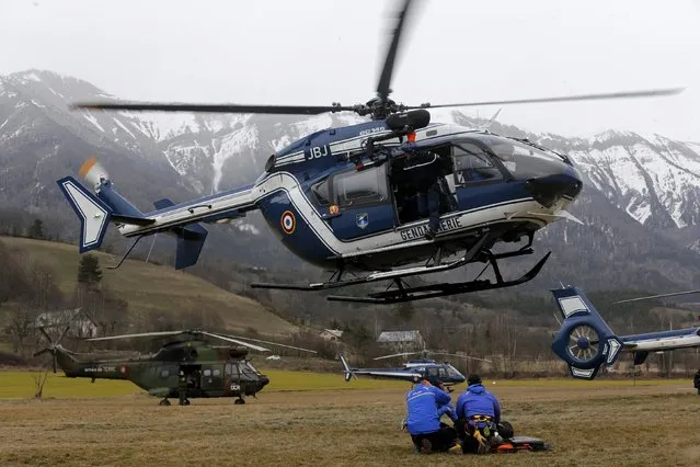 A French rescue helicopter from the French Gendarmerie hovers above a field where Alpine rescue forces gather in front of the French Alps during a rescue operation next to the crash site of an Airbus A320, near Seyne-les-Alpes, March 24, 2015. (Photo by Jean-Peal Pelissier/Reuters)