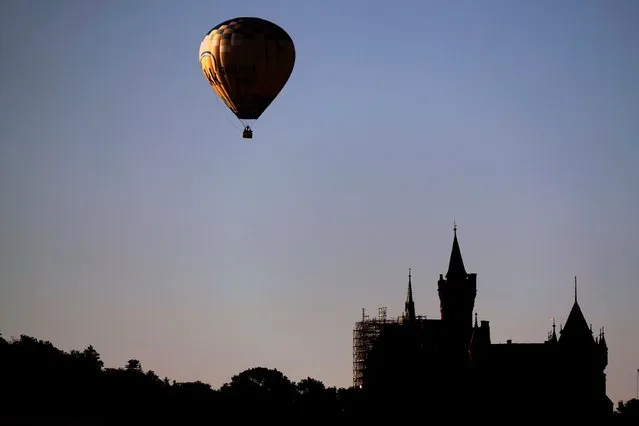 A hot air balloon floats over the castle in Wernigerode at the Harz mountains, Germany, Thursday, August 10, 2023. (Photo by Matthias Schrader/AP Photo)
