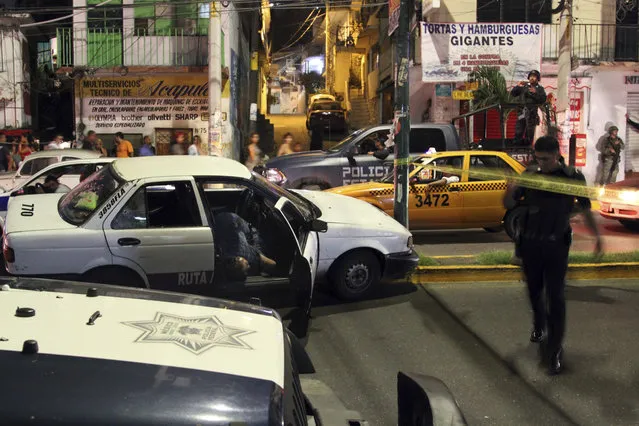 A taxi driver lies dead in his car after being shot shortly before midnight in a busy street in Acapulco early Sunday, January 1, 2017. At least five people were killed over the New Year's weekend in the Mexican resort city of Acapulco, including three men found decapitated in a central neighborhood. (Photo by Bernandino Hernandez/AP Photo)