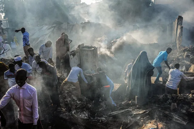 People try to recover items from the remains after a fire broke overnight in Mogadishu's biggest market, the Bakara Market, on January 11, 2019. (Photo by Mohamed Abdiwahab/AFP Photo)