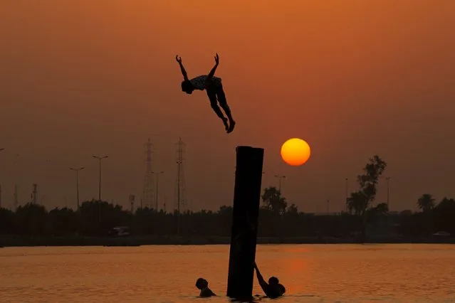 Iraqi youth swim in the Shatt Al-Arab river by the port of Maqil amid a heatwave in the southern Iraqi city of Basra on June 29, 2021. (Photo by Hussein Faleh/AFP Photo)