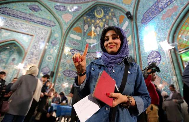 An Iranian woman shows her inked finger after casting her ballot at a polling station in Tehran on February 26, 2016. Iranians began voting across the country in elections billed by the moderate president as vital to curbing conservative dominance in parliament and speeding up domestic reforms after a nuclear deal with world powers. (Photo by Atta Kenare/AFP Photo)