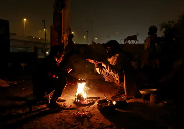 People warm themselves by a fire to escape the cold in Delhi, India January 16, 2017. (Photo by Cathal McNaughton/Reuters)