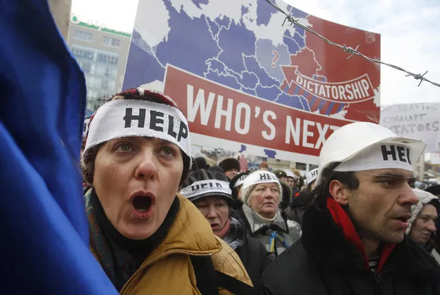 Protesters wearing headbands reading “Help” shout slogans during an action entitled “Impose sanctions – stop the violence” in front of the European Union delegation in Ukraine in Kiev of January 20, 2014. (Photo by Yuriy Kirnichny/AFP Photo)