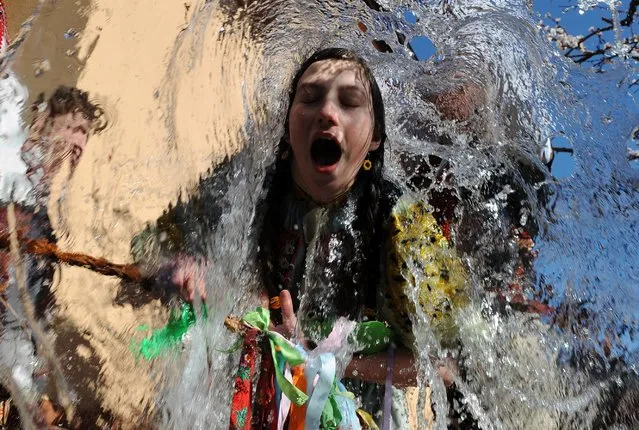 Young Slovaks dressed in traditional costumes throw a bucket of water at a girl as part of Easter celebrations in the village of Trencianska Tepla, 145 km north of Bratislava on  April 9, 2012. (Photo by Samuel Kubani/AFP Photo)
