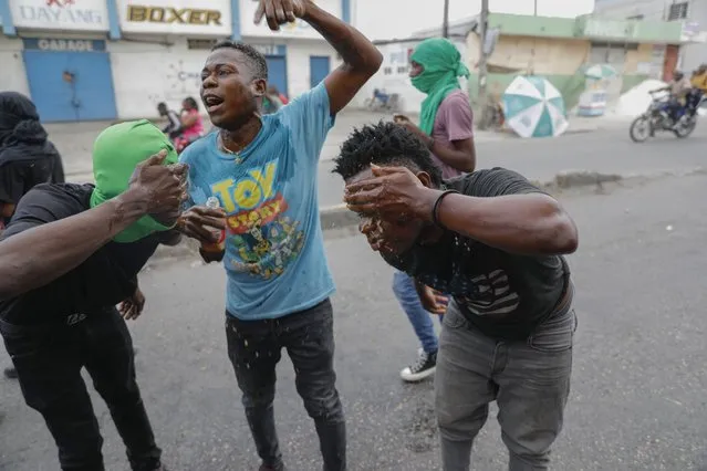 Protesters wipe their faces with water after receiving tear gas fired by police during a protest against Haitian Prime Minister Ariel Henry in Port-au-Prince, Haiti, Monday, February 5, 2024. (Photo by Odelyn Joseph/AP Photo)