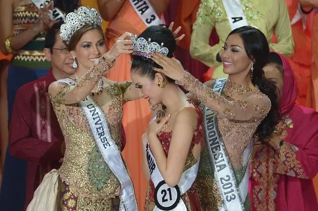 This picture taken in Jakarta on January 29, 2014 shows Miss Indonesia 2014 Elvira Devinamira (C) from East Java being crowned by Miss Indonesia 2013 Wulandari Herman (R) and Miss Universe Maria Gabriela Isler (L) during a grand final of the Miss Indonesia 2014 beauty contest in Jakarta. Elvira Devinamira of East Java was crowned as Miss Indonesia 2014 and will compete in Miss Universe 2014. (Photo by Adek Berry/AFP Photo)