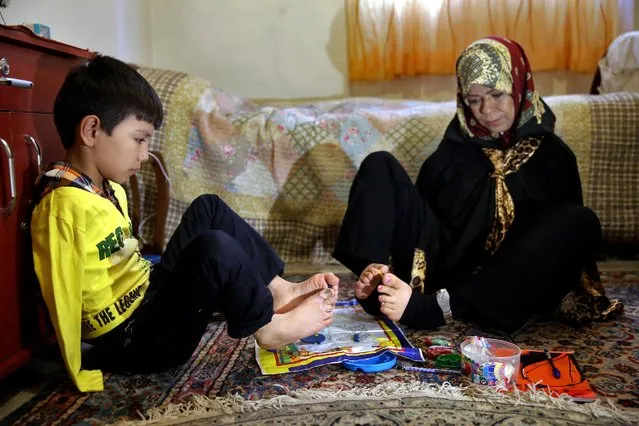 In this picture taken on January 21, 2015, Zohreh Etezadossaltaneh, right, who was born without arms, teaches 9-year old Afghan boy Roohollah Jafar, how to use his feet during a lesson at her home, in Tehran, Iran. (Photo by Ebrahim Noroozi/AP Photo)