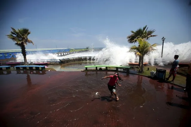 A tourist runs as a wave crashes on La Libertad malecon May 3, 2015. (Photo by Jose Cabezas/Reuters)