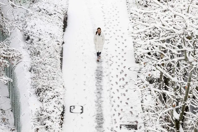 A woman walks along a footpath after snowfall in Seoul on February 22, 2024. (Photo by Anthony Wallace/AFP Photo)