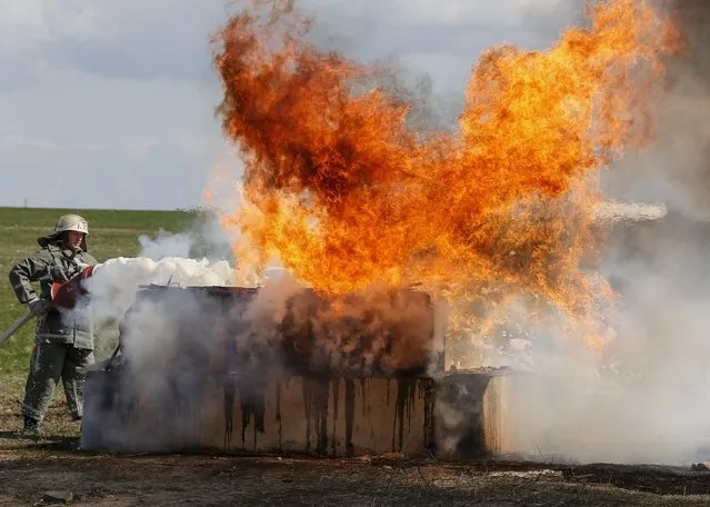 A firefighter extinguishes fire as he participate in a drill simulating a fire incident near a gas compressor station belonging to Naftogaz in the village of Boyarka, outside Kiev, April 22, 2015. (Photo by Gleb Garanich/Reuters)