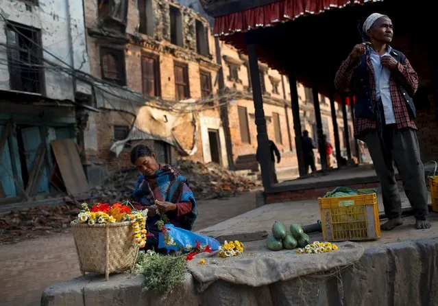A woman (L) sells flowers as a man smoke , in the early morning hours in  Bhaktapur near Kathmandu, Nepal, May 14, 2015. (Photo by Ahmad Masood/Reuters)