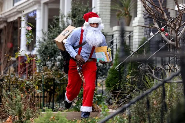 Postal worker Eddie Smith, dressed as Santa Claus, waves to a neighbor on his mail route in Washington, U.S., December 21, 2021. (Photo by Evelyn Hockstein/Reuters)