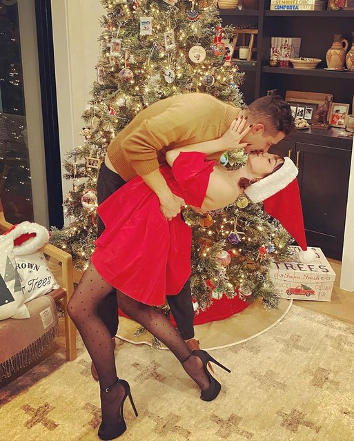 American actress Sarah Hyland and her fiancé, TV personality Wells Adams, share a kiss in front of the Christmas tree on December 27, 2021. (Photo by sarahhyland/Instagram)