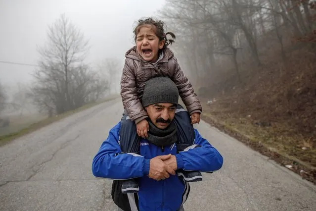 Father carries his crying daughter as members of a migrant family from Afghanistan approach Croatia's border from Bosnian side in an attempt to cross into EU by foot, known as “The Game” near Bosanska Bojna on January 6, 2021 in Bosnia and Herzegovina. The family crossed into Croatia only to be pushed back to Bosnia by Croatian police few hours later. There are currently some 3,000 refugees with children sleeping in abandoned houses and temporary accommodations in sub-zero temperatures in northern Bosnia. Many attempt crossing into Croatia to claim asylum in the European Union. For years the EU has been deeply divided over its migration policy. (Photo by Damir Sagolj/Getty Images)
