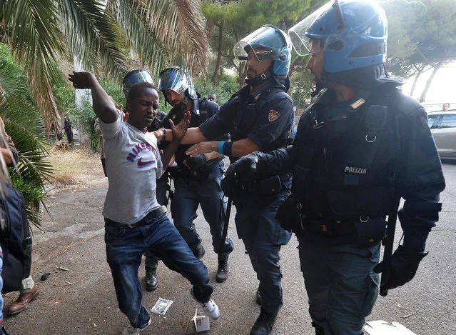 Italian police officers remove a migrant in Ventimiglia, at the Italian-French border Tuesday, June 16, 2015. Police at Italy's Mediterranean border with France have forcibly removed some of the African migrants who have been camping out for days in hopes of continuing their journeys farther north. The migrants, mostly from Sudan and Eritrea, have been camped out for five days after French border police refused to let them cross. (Luca Zennaro/ANSA via AP)