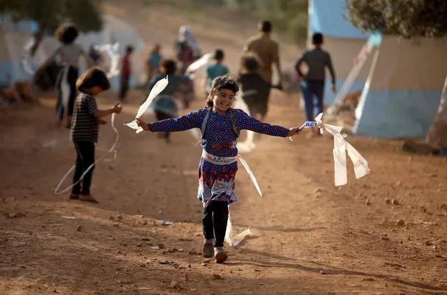 Displaced Syrian children play in a camp for internally displaced people near Kah, in the northern Idlib province near the border with Turkey on June 3, 2019 on the eve of Eid al-Fitr, which marks the end of the Muslim holy fasting month of Ramadan. The conflict in Syria has killed more than 370,000 people and displaced millions since it started in 2011. (Photo by Aaref Watad/AFP Photo)