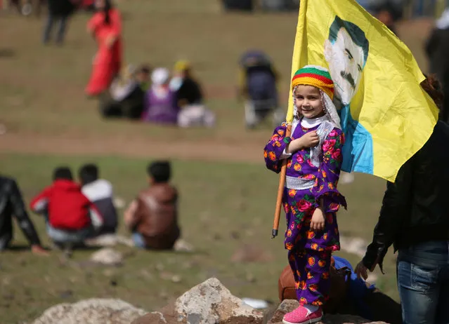 A girl carries a flag depicting jailed Kurdish leader Abdullah Ocalan of the Kurdistan Workers Party (PKK) during a celebration for the spring festival of Newroz, in al-Darbasiyah town, on the Syrian-Turkish border, Syria on March 21, 2017. (Photo by Rodi Said/Reuters)