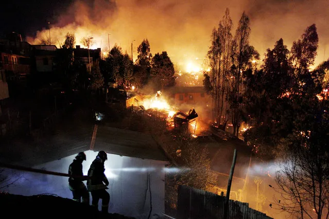 Firefighters work to put out a fire in Valparaiso city, northwest of Santiago, April 13, 2014. At least 12 people were killed and 2,000 houses destroyed over the weekend by a fire that devastated parts of the Chilean port city of Valparaiso, as authorities evacuated thousands and sent in aircraft to battle the blaze. (Photo by Eliseo Fernandez/Reuters)