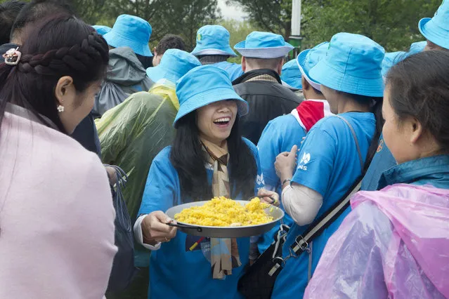 A Chinese conglomerate Tiens Group employee smiles after being served Paella in Madrid, Spain, Friday, May 6, 2016. (Photo by Paul White/AP Photo)