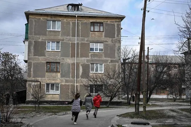 Three women run for cover during shelling in the town of Schastia, near the eastern Ukraine city of Lugansk, on February 22, 2022, a day after Russia recognised east Ukraine's separatist republics and ordered the Russian army to send troops there as “peacekeepers”. (Photo by Aris Messinis/AFP)