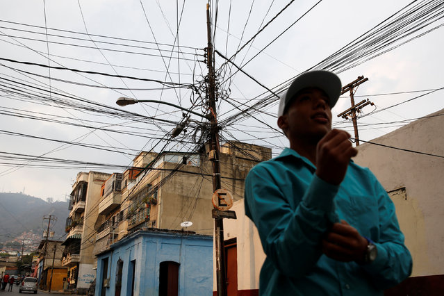 A man walks past an electric pole with overhead power cables in Caracas, Venezuela, April 2, 2016. (Photo by Carlos Garcia Rawlins/Reuters)