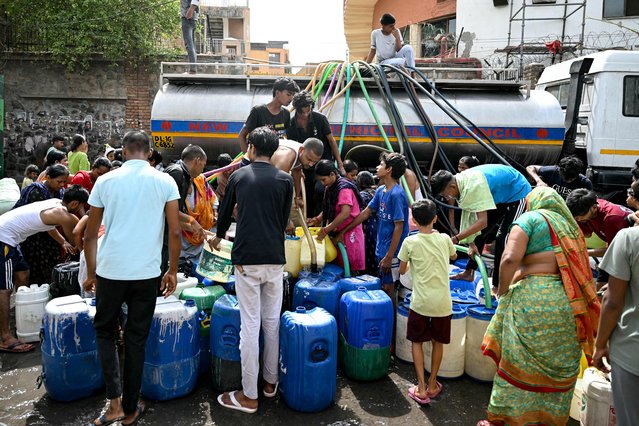 Residents fill their containers with water supplied by a municipal tanker in New Delhi on June 19, 2024 amid heatwave. Searing heatwave temperatures in northern India pushed power demand to a record high, the government said on June 18, with residents of the capital New Delhi also struggling with water shortages. (Photo by Money Sharma/AFP Photo)