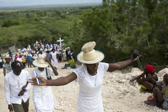 A woman stretches out her arms in prayer as balances a stone on her head as a form of penance during a Good Friday ritual, in Ganthier, Haiti, Friday, April 14, 2017. Thousands of Haitians flock to mount Calvaire Miracle with rocks balanced on their heads, to pray and seek renewal in one of the spiritually-steeped country’s biggest annual pilgrimages. (Photo by Dieu Nalio Chery/AP Photo)