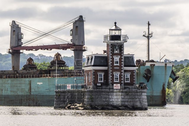 A ship passes the Hudson Athens Lighthouse, Wednesday, June 12, 2024, in Hudson, N.Y. The 150-year-old lighthouse is in danger of toppling into the water, and advocates for the lighthouse in the middle of Hudson River are urgently trying to save it. (Photo by Julia Nikhinson/AP Photo)