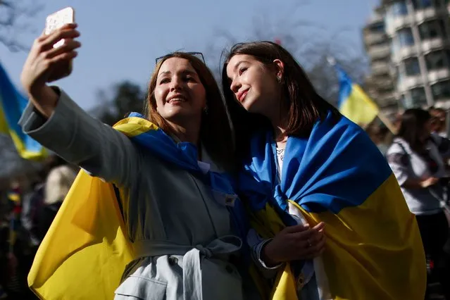 Women wrapped in Ukrainian flags take a selfie during a demonstration in support of Ukraine, amid Russia's invasion of Ukraine, in central London, Britain on March 26, 2022. (Photo by Tom Nicholson/Reuters)