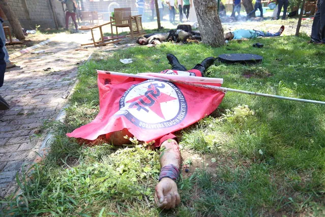 A victim, with a flag of the left-wing Federation of Socialist Youth Associations covering him, lies on the ground following an explosion in Suruc, in the southeastern Sanliurfa province, Turkey, July 20, 2015. The explosion outside a cultural centre in the Turkish town of Suruc near the border with Syria killed at least 20 people and wounded many more on Monday, witnesses told Reuters, in what local officials said may have been a suicide bombing. (Photo by Ozcan Soysal/Reuters/Depo)